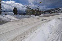 an empty snowy road under ski lift at the top of a hill in winter time