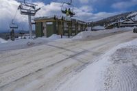 an empty snowy road under ski lift at the top of a hill in winter time