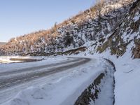 a winding road with a truck on it covered in snow at the side of a hill