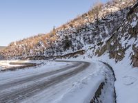 a winding road with a truck on it covered in snow at the side of a hill