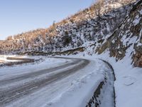 a winding road with a truck on it covered in snow at the side of a hill