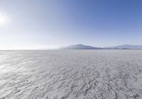 large expanse with clear water on it surrounded by snow covered hills and mountains in the background