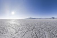 large expanse with clear water on it surrounded by snow covered hills and mountains in the background