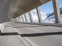 this is a long tunnel in the mountains where there is snow covering the ground and a person riding a skateboard
