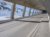 this is a long tunnel in the mountains where there is snow covering the ground and a person riding a skateboard
