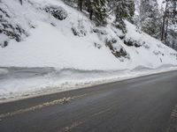snow is melting on the side of a mountain with trees on top and a road below
