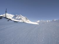 a skier going down a ski slope in the snow on a sunny day, with a mountain in the background