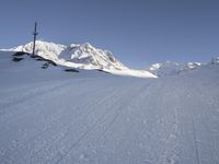 a skier going down a ski slope in the snow on a sunny day, with a mountain in the background