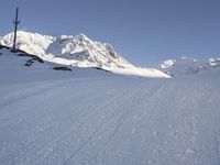 a skier going down a ski slope in the snow on a sunny day, with a mountain in the background