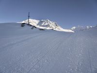 a skier going down a ski slope in the snow on a sunny day, with a mountain in the background