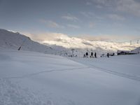 a snow covered mountain is in the background with people skiing down it and a lift to the top of the slope