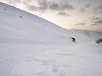 a man riding a snowboard down the side of a snow covered hill while skiing