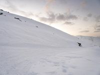 a man riding a snowboard down the side of a snow covered hill while skiing