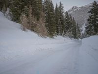 a person with skis stands on a snowy road in the snow at the bottom of a hill