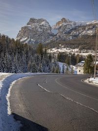 the roadway is empty, with some snow on it and a large mountain in the background