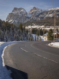 the roadway is empty, with some snow on it and a large mountain in the background