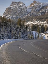 the roadway is empty, with some snow on it and a large mountain in the background