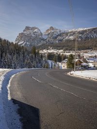 the roadway is empty, with some snow on it and a large mountain in the background