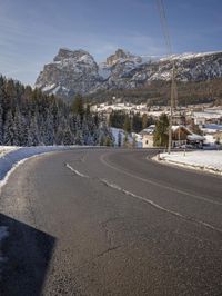 the roadway is empty, with some snow on it and a large mountain in the background