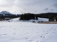 snow on the ground and mountains are visible in the background, while a cross - country skier is hiking through snow