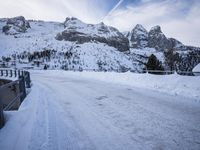 snow covers the road as seen from a bridge in front of a snowy mountain range