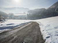 a snow covered road leads through a beautiful snowy landscape surrounded by evergreens and mountains