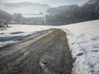 a snow covered road leads through a beautiful snowy landscape surrounded by evergreens and mountains