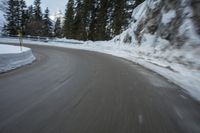 the speed of a motorcycle going down a snowy road by a snow bank in winter