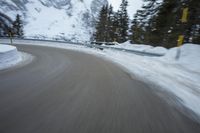 the speed of a motorcycle going down a snowy road by a snow bank in winter