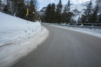 the speed of a motorcycle going down a snowy road by a snow bank in winter