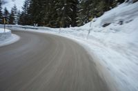 the speed of a motorcycle going down a snowy road by a snow bank in winter