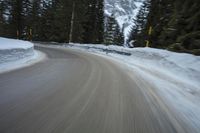 the speed of a motorcycle going down a snowy road by a snow bank in winter