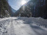 a long road that has been cleared by snow next to some woods and mountains with trees in the background