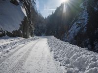 a long road that has been cleared by snow next to some woods and mountains with trees in the background