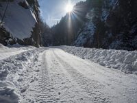 a long road that has been cleared by snow next to some woods and mountains with trees in the background