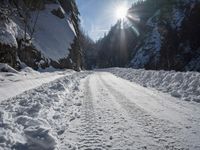 a long road that has been cleared by snow next to some woods and mountains with trees in the background