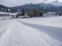 the snow and ski slope is covered in tracks and snow, with mountains and houses in the background