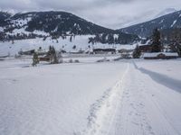 the snow and ski slope is covered in tracks and snow, with mountains and houses in the background
