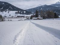 the snow and ski slope is covered in tracks and snow, with mountains and houses in the background