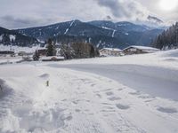 the snow and ski slope is covered in tracks and snow, with mountains and houses in the background