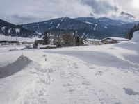 the snow and ski slope is covered in tracks and snow, with mountains and houses in the background