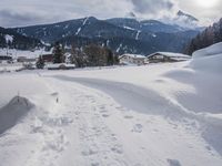 the snow and ski slope is covered in tracks and snow, with mountains and houses in the background