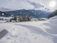 the snow and ski slope is covered in tracks and snow, with mountains and houses in the background