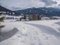 the snow and ski slope is covered in tracks and snow, with mountains and houses in the background