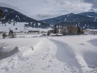 the snow and ski slope is covered in tracks and snow, with mountains and houses in the background