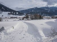 the snow and ski slope is covered in tracks and snow, with mountains and houses in the background