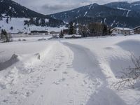 the snow and ski slope is covered in tracks and snow, with mountains and houses in the background