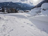 the snow and ski slope is covered in tracks and snow, with mountains and houses in the background