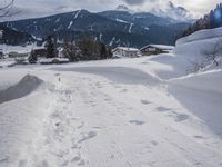 the snow and ski slope is covered in tracks and snow, with mountains and houses in the background