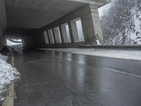 a motorcycle is parked by a tunnel near some snow covered trees outside of the tunnel